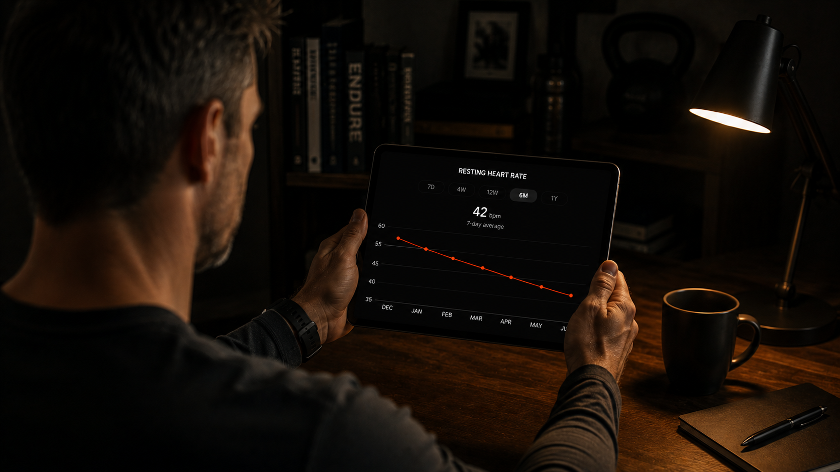 Athlete reviewing resting heart rate trend data on a device in a dim study